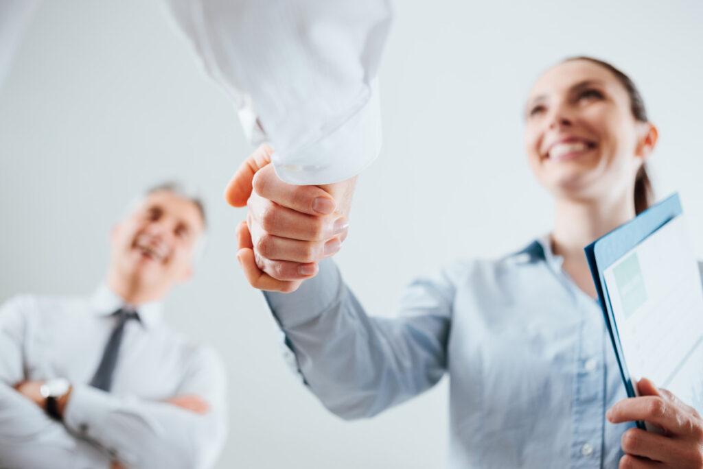 a woman shaking hands and a man smiling with an Independent Insurance Agent in Calhoun, GA, Alpharetta, Ballground, Woodstock, Canton, Jasper, GA